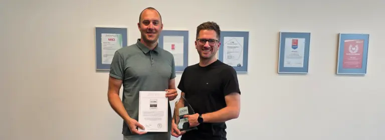 MID GmbH | Leading Employer 2026 – Stefan Klein und Patrick Düber präsentieren Urkunde und Trophäe vor einer Wand mit gerahmten Urkunden; Header-Bild zur News über die Auszeichnung als attraktiver Arbeitgeber.
